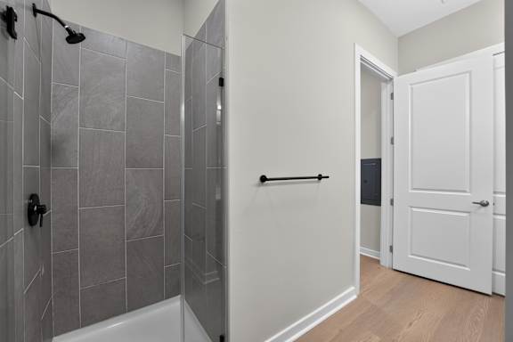 A bathroom with a walk-in shower and a white door.