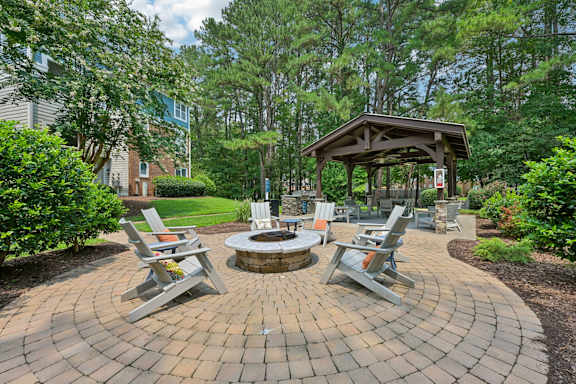 A fire pit is surrounded by four chairs in a backyard.