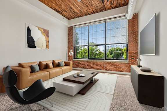 A living room with a brown leather couch, a black chair, a wooden coffee table, and a flat screen TV mounted on the wall  Tindeco Warf, Baltimore Maryland