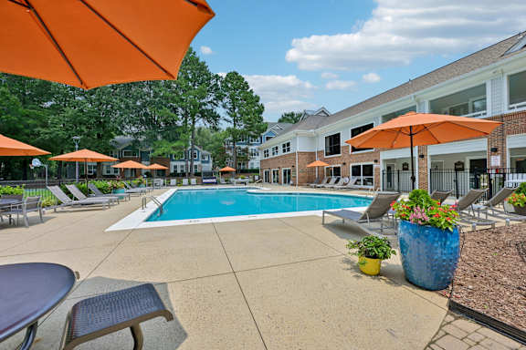 A pool surrounded by orange umbrellas and chairs.