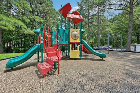 A playground with a green slide and red and yellow play structures.