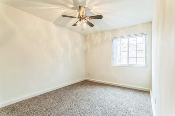 A room with a ceiling fan and a window.
