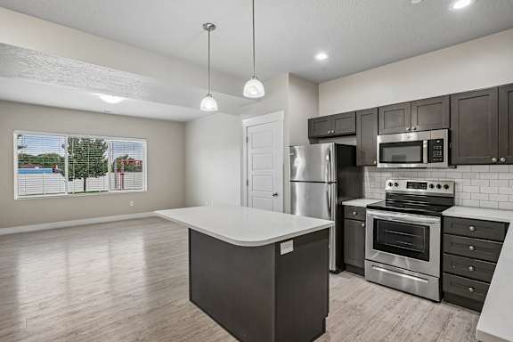 A kitchen with a white island and stainless steel appliances.