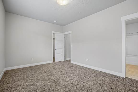 A room with a carpeted floor and a doorway leading to another room.