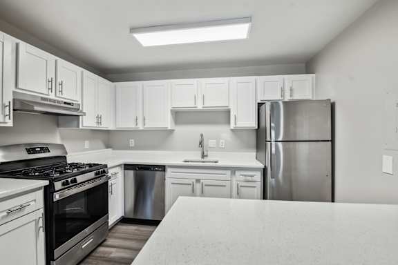 A kitchen with white cabinets and a stainless steel refrigerator.
