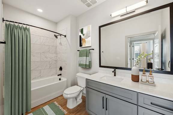 A bathroom with a white toilet, a white sink, and a green shower curtain.