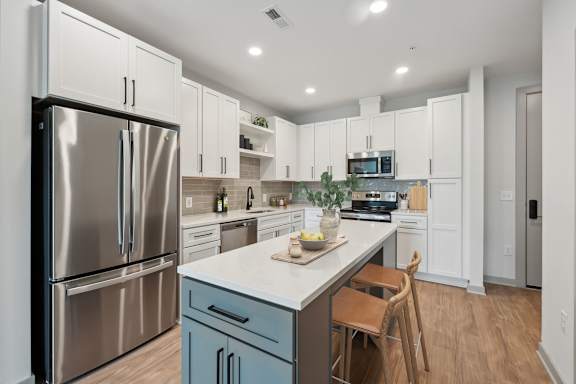 A modern kitchen with a stainless steel refrigerator and a marble countertop.