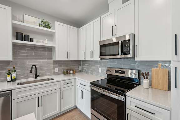 A kitchen with white cabinets and a black stove top oven.
