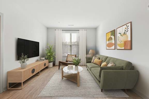 A living room with a green couch, a wooden table, and a flat screen TV mounted on the wall.