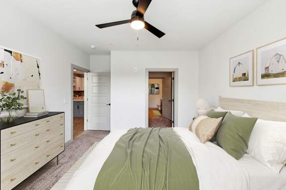 A bedroom with a bed, dresser, and ceiling fan.