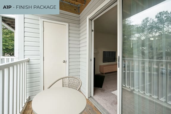 A white table and chair are on a deck with a glass door leading to a living room.