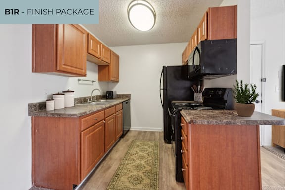A kitchen with brown cabinets and a black microwave.