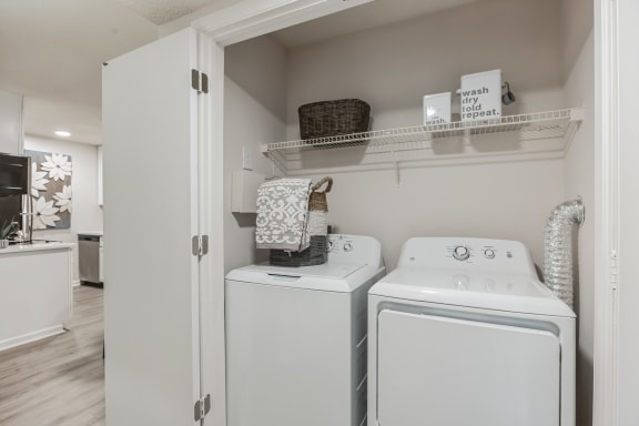 a white washer and dryer in a laundry room with a shelf above it at St. Andrews Reserve, Wilmington