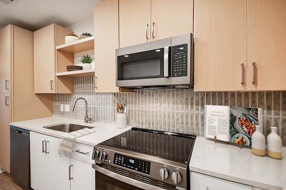 A kitchen with a black stove top oven and a black microwave above it at Hawkins Press Apartments, North Carolina, 28203