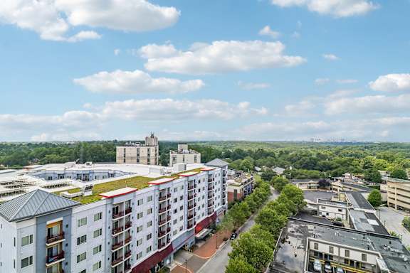 A view of a city from a high vantage point with buildings, roads, and trees.