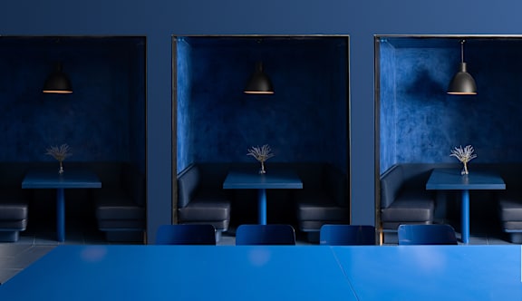 A blue table is in the middle of a room with three chairs and three lamps at Miles at Ybor Apartments, Tampa, FL, 33605