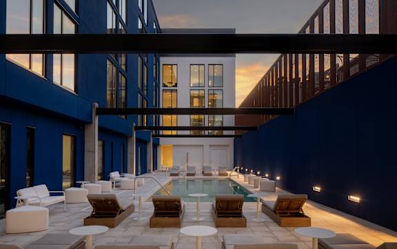 A modern outdoor pool area with lounge chairs and tables at Miles at Ybor Apartments, Tampa