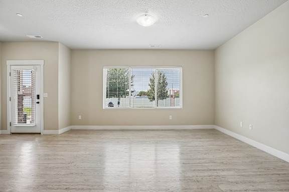 A room with a wooden floor and a window with blinds.