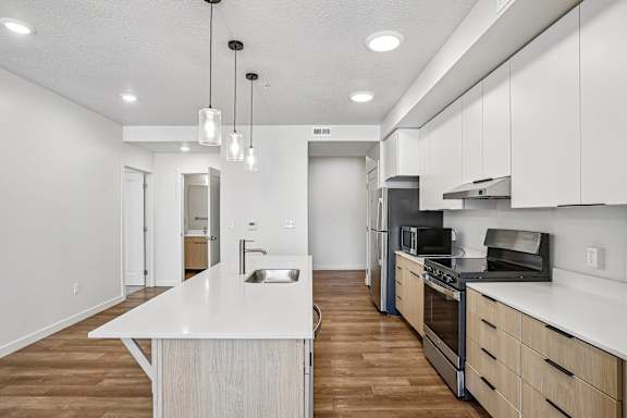 A modern kitchen with a white countertop and stainless steel appliances.