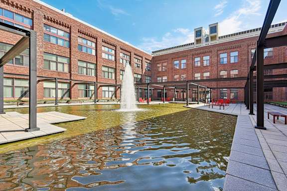 A fountain in the middle of a courtyard surrounded by buildings at Tindeco, Wharf, Baltimore, MD 21224