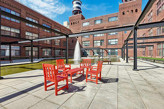 A courtyard with red chairs and a fountain at Tindeco, Wharf, Baltimore, MD 21224