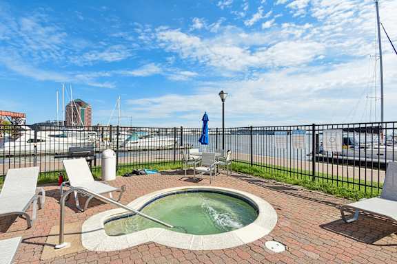 A hot tub sits on a brick patio with chairs around it at Tindeco Wharf, Maryland, 21224