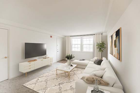 A modern living room with a white couch, a television, and a rug.