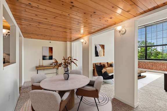 a dining room and living room with a wooden ceiling and a table and chairs at Tindeco Wharf, Baltimore, 21224