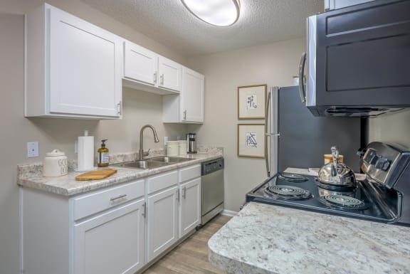 a kitchen with white cabinets and granite countertops at St. Andrews Reserve, Wilmington, North Carolina