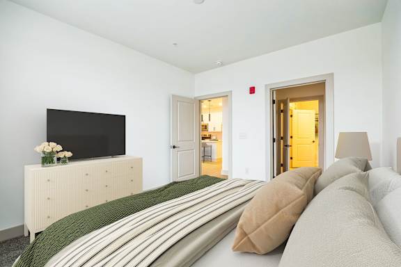 A bedroom with a bed, a dresser, and a television