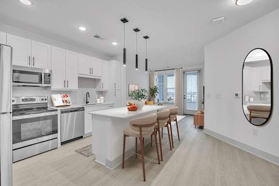 A modern kitchen with a white island and wooden chairs