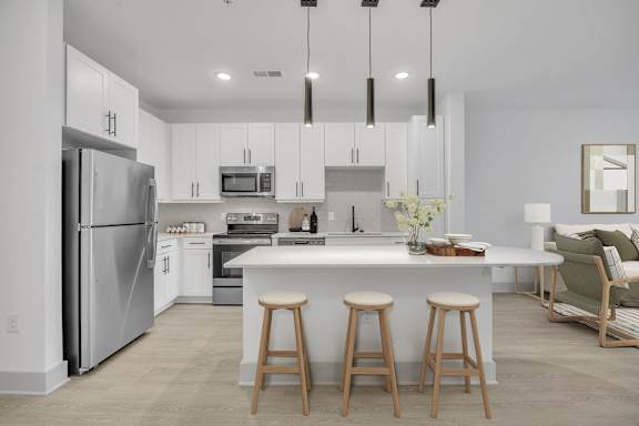A modern kitchen with a refrigerator, microwave, oven, and a dining table with chairs