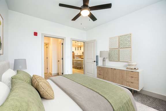 A bedroom with a bed, pillows, and a ceiling fan