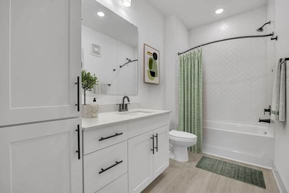 A white bathroom with a green rug on the floor
