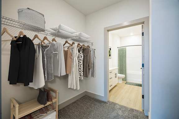 A white room with clothes hanging up and a bench underneath