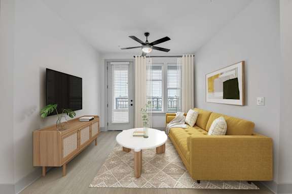 A living room with a yellow couch, a white coffee table, and a flat-screen TV