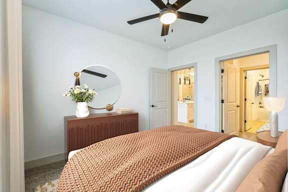A bedroom with a bed, a dresser, and a ceiling fan
