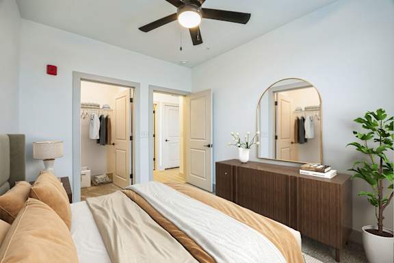 A bedroom with a bed, dresser, mirror, and a plant