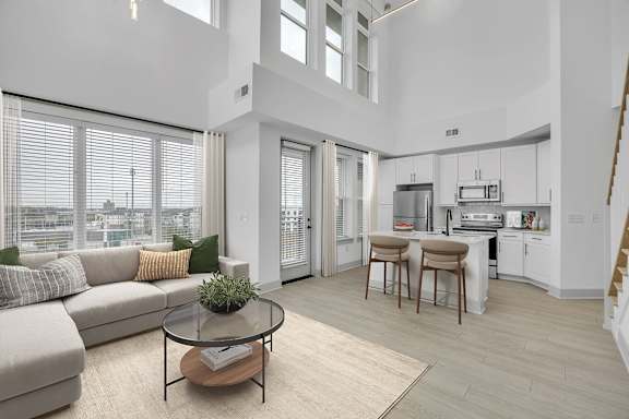 A modern living room with a glass table and a grey sofa