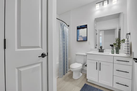 A bathroom with a white toilet, sink, and cabinets