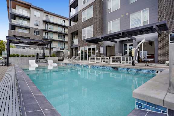 A swimming pool in a residential area with a building in the background.