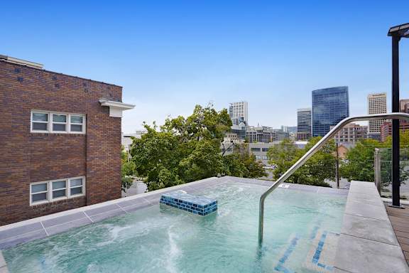 A hot tub on a balcony with a city skyline in the background.