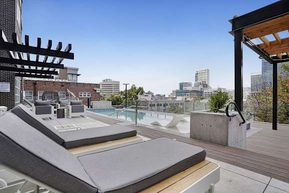 A rooftop patio with a hot tub and a view of the city.