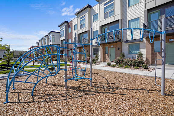 A playground with a blue swing set in front of apartment buildings.