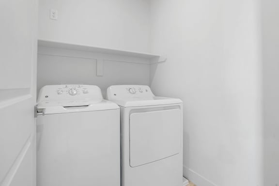Two white front loading washing machines in a laundry room.