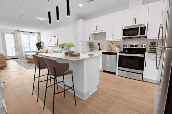 a kitchen with white cabinets and a white island with bar stools at Metropolitan at the Riverwalk, Wilmington, NC