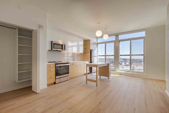 A kitchen with wooden floors and a large window overlooking a cityscape.