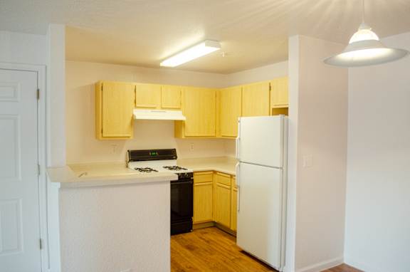 A kitchen with yellow cabinets and white appliances.