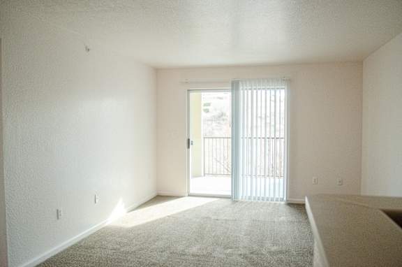 A room with a carpeted floor and a sliding glass door.
