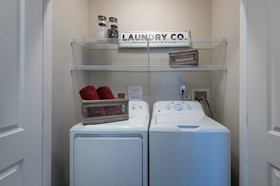A laundry room with two washing machines and a shelf with containers on it.
